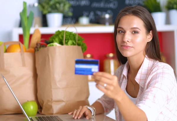 Smiling woman online shopping using tablet and credit card in kitchen — Stock Photo, Image