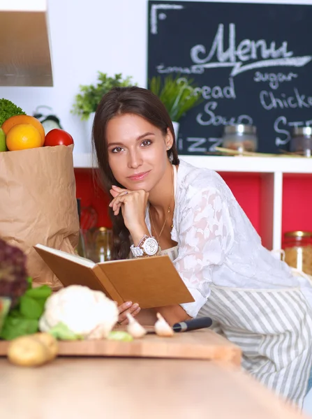 Giovane donna che legge il libro di cucina, alla ricerca di ricetta — Foto Stock