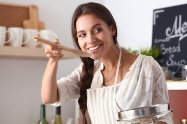 Mutfakta ahşap kaşıkla yemek pişiren kadın