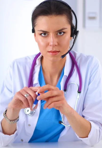 Médico usando fone de ouvido sentado atrás de uma mesa com laptop — Fotografia de Stock