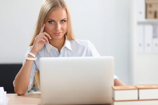 Atraktivní podnikatelka sedící na stole s laptopem v kanceláři — Stock fotografie