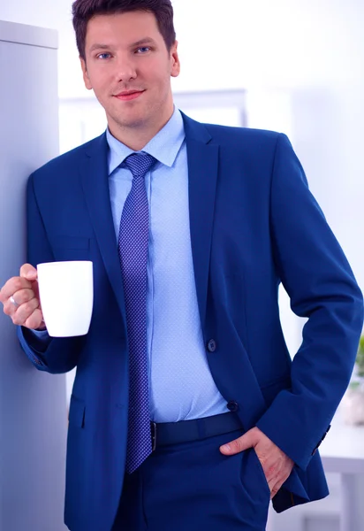一杯のコーヒーで立っている笑顔の実業家 — ストック写真