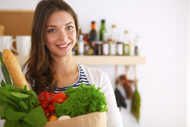 Elinde sebzeli alışveriş torbası tutan genç bir kadın. 