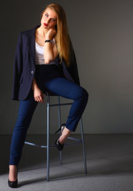 Genç bir kadın sandalyede oturuyor.