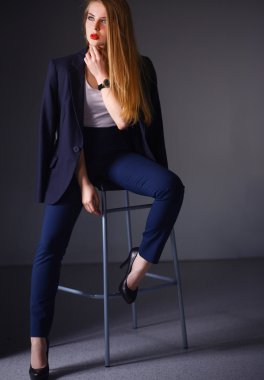 Genç bir kadın sandalyede oturuyor.