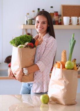 Elinde sebzeli alışveriş torbası tutan genç bir kadın. 