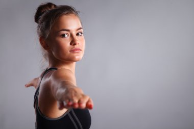 Genç kadının gri arka plan üzerinde Yoga egzersiz yapması