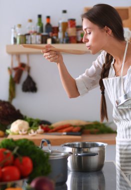Mutfakta ahşap kaşıkla yemek pişiren kadın