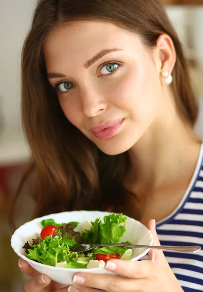 Молодая женщина ест салат и держит смешанный салат — стоковое фото