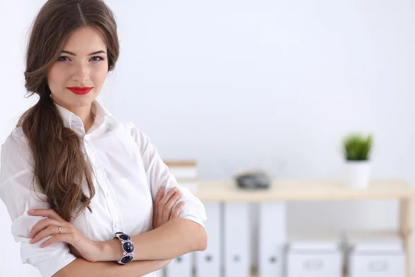 Attractive businesswoman standing near wall in office — Stock Photo, Image