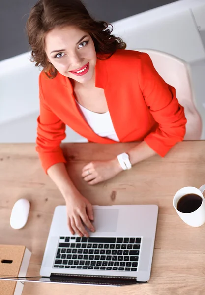 Mulher atraente sentada na mesa no escritório, trabalhando com computador portátil — Fotografia de Stock