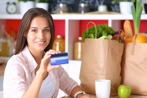 Mulher sorrindo compras on-line usando tablet e cartão de crédito na cozinha — Fotografia de Stock