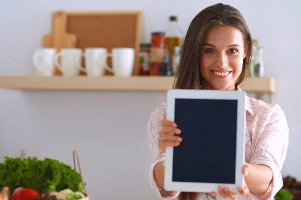 Mutfakta yemek yapmak için tablet bilgisayar kullanan genç bir kadın. — Stok fotoğraf