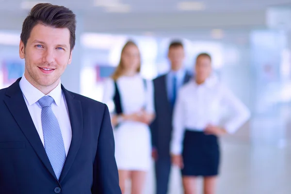 Porträt eines jungen Geschäftsmannes im Amt mit Kollegen im Hintergrund — Stockfoto