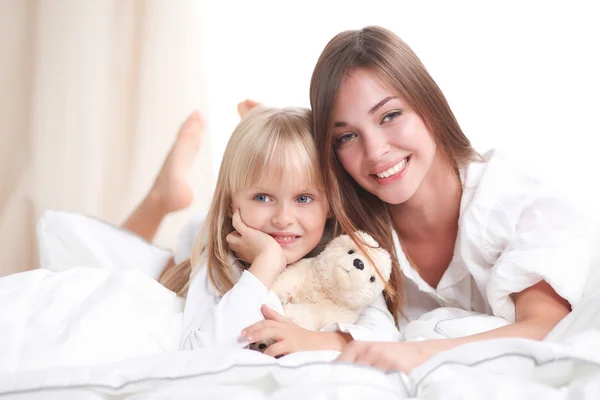 Nő és fiatal lány feküdt az ágyban mosolyogva — Stock Fotó