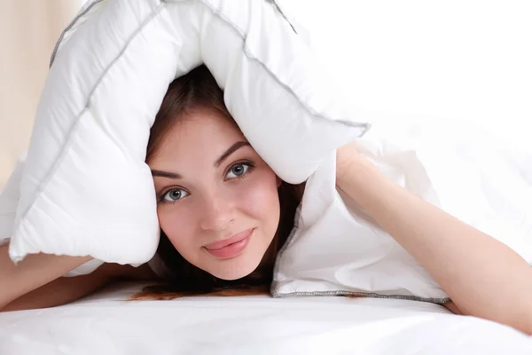 Femme couchée sur le lit et fermant ses oreilles avec un oreiller — Photo