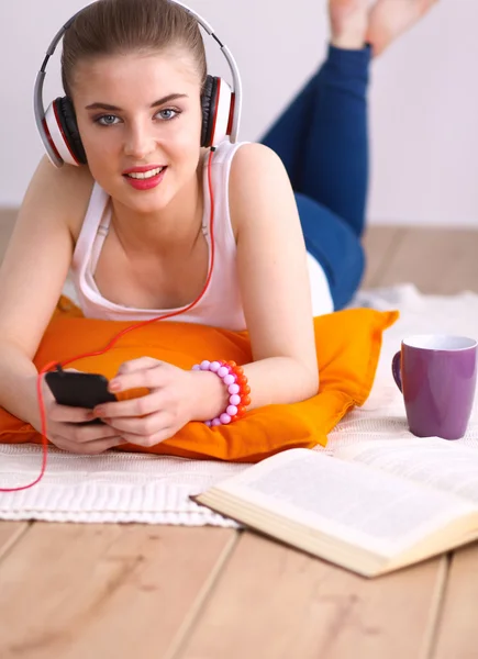 Ung kvinna liggande på golvet och lyssnar på musik — Stockfoto
