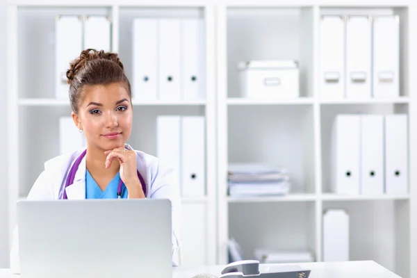 Vrouwelijke arts zit op het bureau en werkt een laptop in het ziekenhuis — Stockfoto