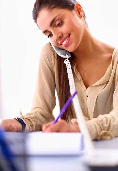 Young businesswoman sitting at the desk and talking on phone — Stock Photo, Image