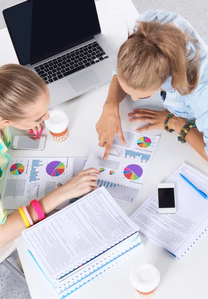 Due donne che lavorano insieme in ufficio, sedute sulla scrivania — Foto Stock