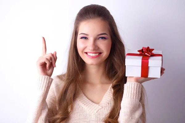 Jonge vrouw gelukkig glimlach houden de doos van de gift in handen, permanent over grijze achtergrond — Stockfoto