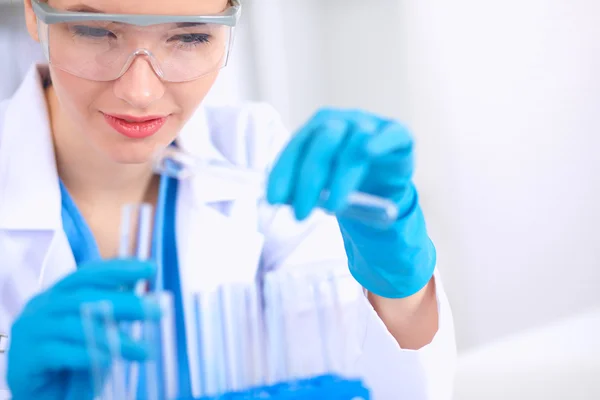 Woman researcher is surrounded by medical vials and flasks, isolated on white background — Stock Photo, Image