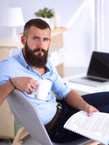 Ung affärsman sitter på stol med bok i office — Stockfoto