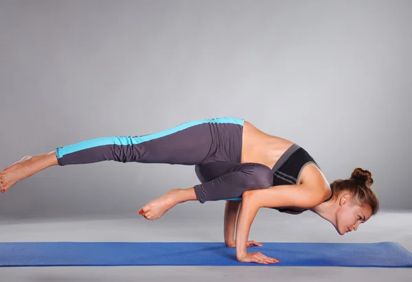 Young woman doing yoga exercise on gray background — Stock Photo, Image