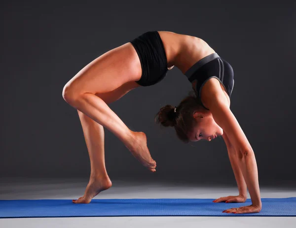 Mujer joven haciendo ejercicio de yoga en la estera — Foto de Stock