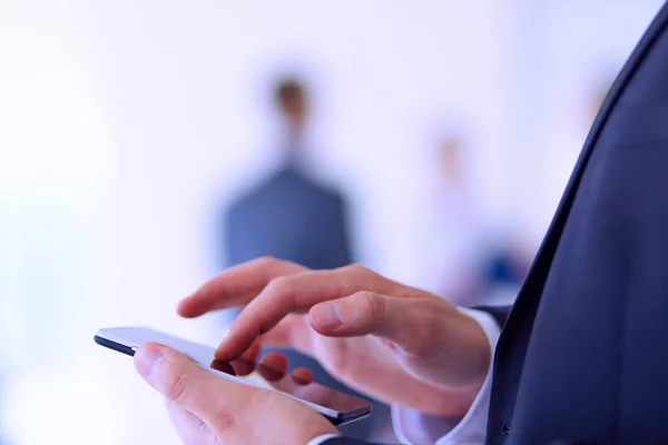 Porträt eines jungen Geschäftsmannes mit Handy im Büro und Kollegen im Hintergrund — Stockfoto