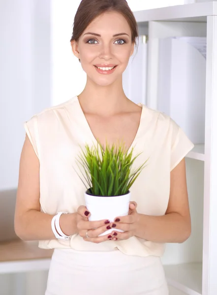 Mulher bonita que prende o potenciômetro com uma planta, estando — Fotografia de Stock