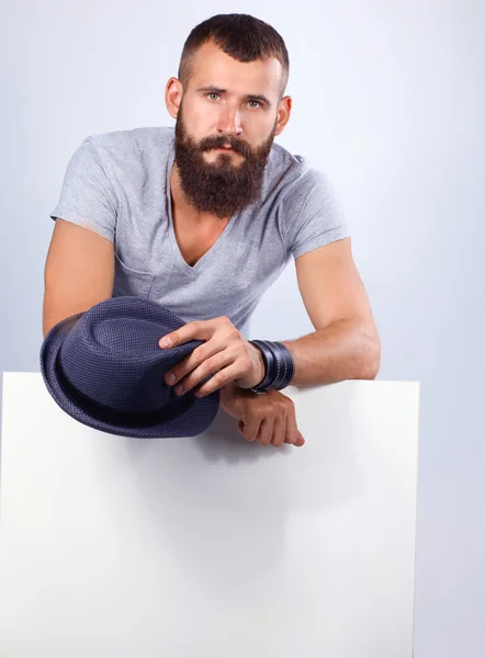 Portrait of young man in hat standing near blank, isolated on white background — Stock Photo, Image