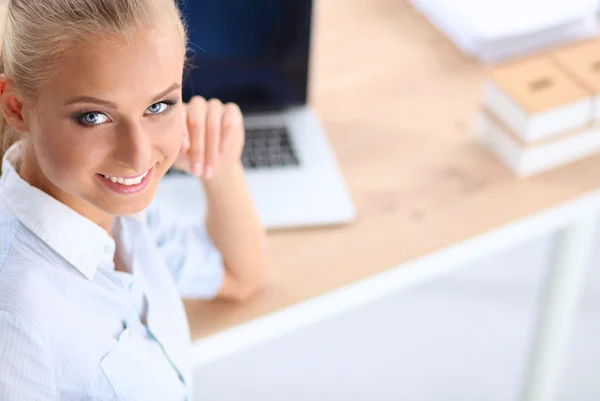 Atractiva mujer de negocios sentada en un escritorio con portátil en la oficina —  Fotos de Stock
