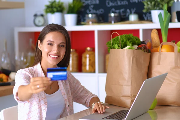 Smiling woman online shopping using tablet and credit card in kitchen — Stock Photo, Image