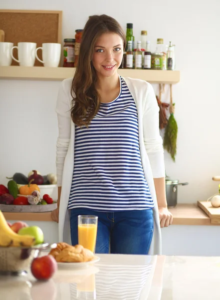 Ung kvinna med glas juice och kakor stående i köket — Stockfoto