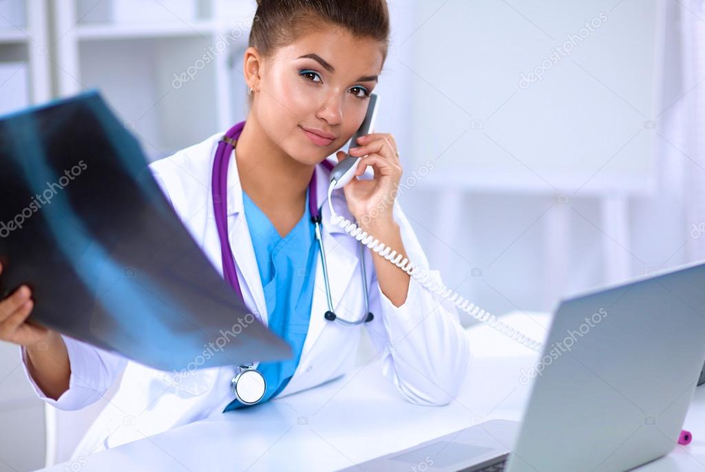 Young female doctor studying x-ray image sitting on the desk