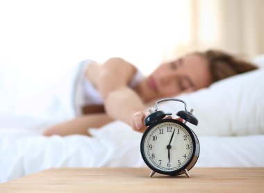 Evdeki yatak odasında uyuyan genç kadın ve çalar saat.