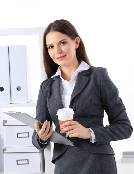 Приваблива молода бізнес-леді стоїть біля столу з текою в офісі — стокове фото