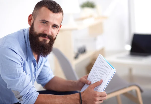 Jonge zakenman zittend op een stoel met boek in office — Stockfoto