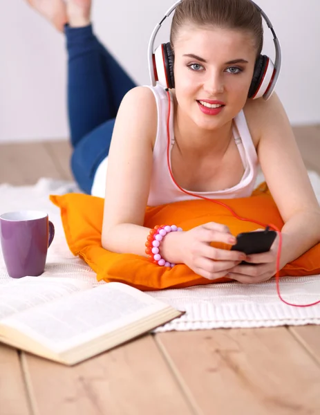 Ung kvinna liggande på golvet och lyssnar på musik — Stockfoto