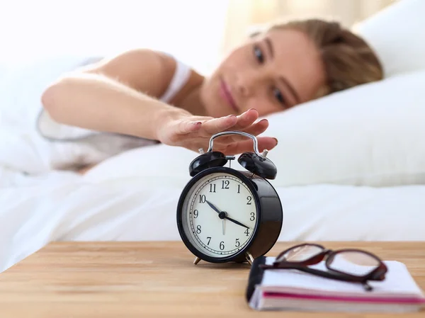 Jeune femme endormie et réveil dans la chambre à coucher à la maison — Photo