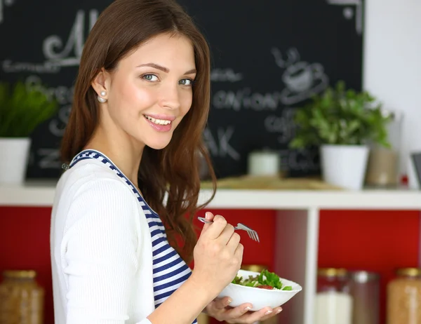 Jovem comendo salada e segurando uma salada mista — Fotografia de Stock