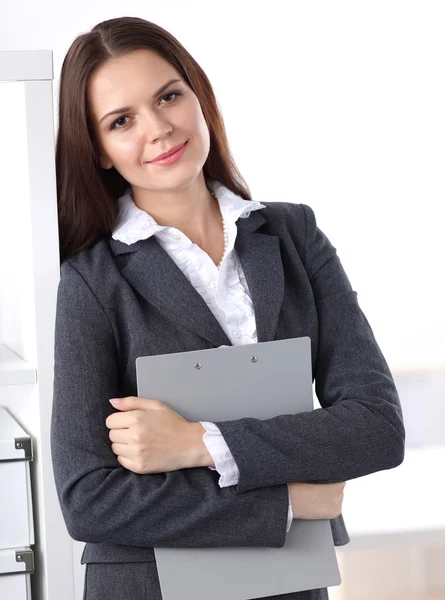 オフィスのフォルダと机の近くに立つ魅力的な若いビジネスマンの女性 — ストック写真