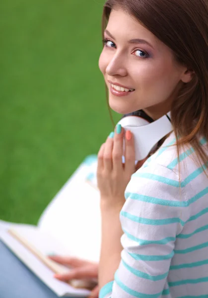 Ung kvinna med bärbar dator sitter på grönt gräs — Stockfoto