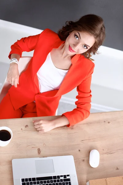 Attraktive Frau sitzt im Büro am Schreibtisch und arbeitet mit Laptop — Stockfoto