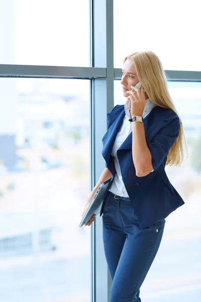 Geschäftsfrau steht mit Dokumenten in der Hand gegen Bürofenster — Stockfoto