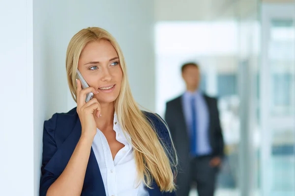 Businesswoman standing against office window holding documents in hand — Stock Photo, Image