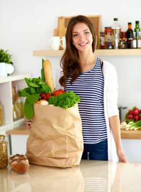 Genç bir kadın mutfakta duruyor.