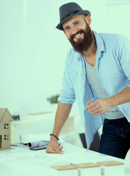 Portrait of male designer in hat with blueprints at desk — Stock Photo, Image