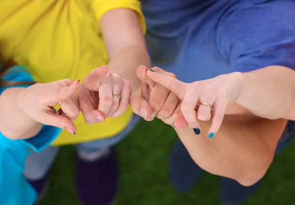 Group of young people standing on green grass pointing up — Stock Photo, Image